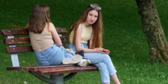 Teens talking on a park bench.